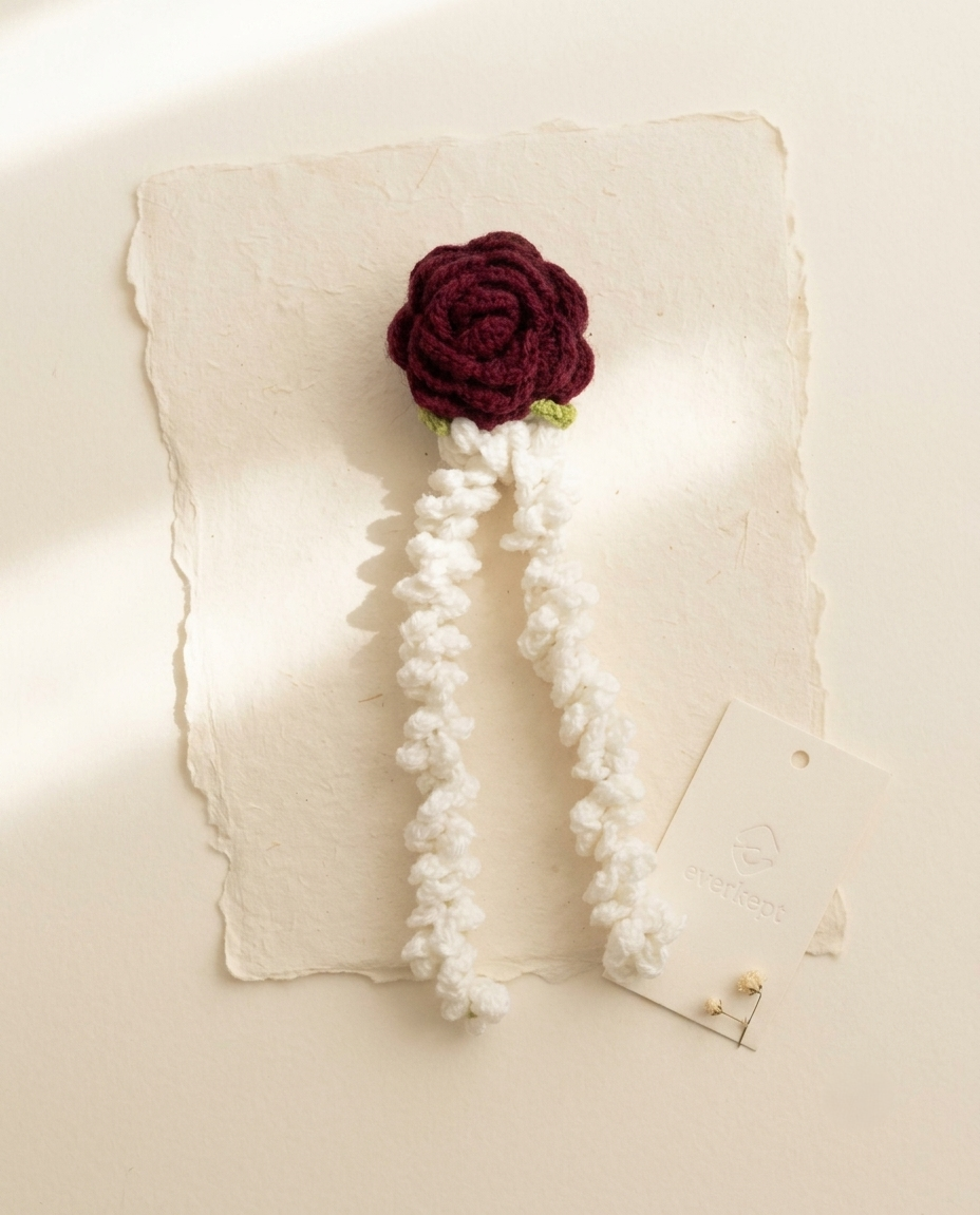 Crochet gajra with a dark red rose and two white mogra strands, on handmade paper with an Everkept tag