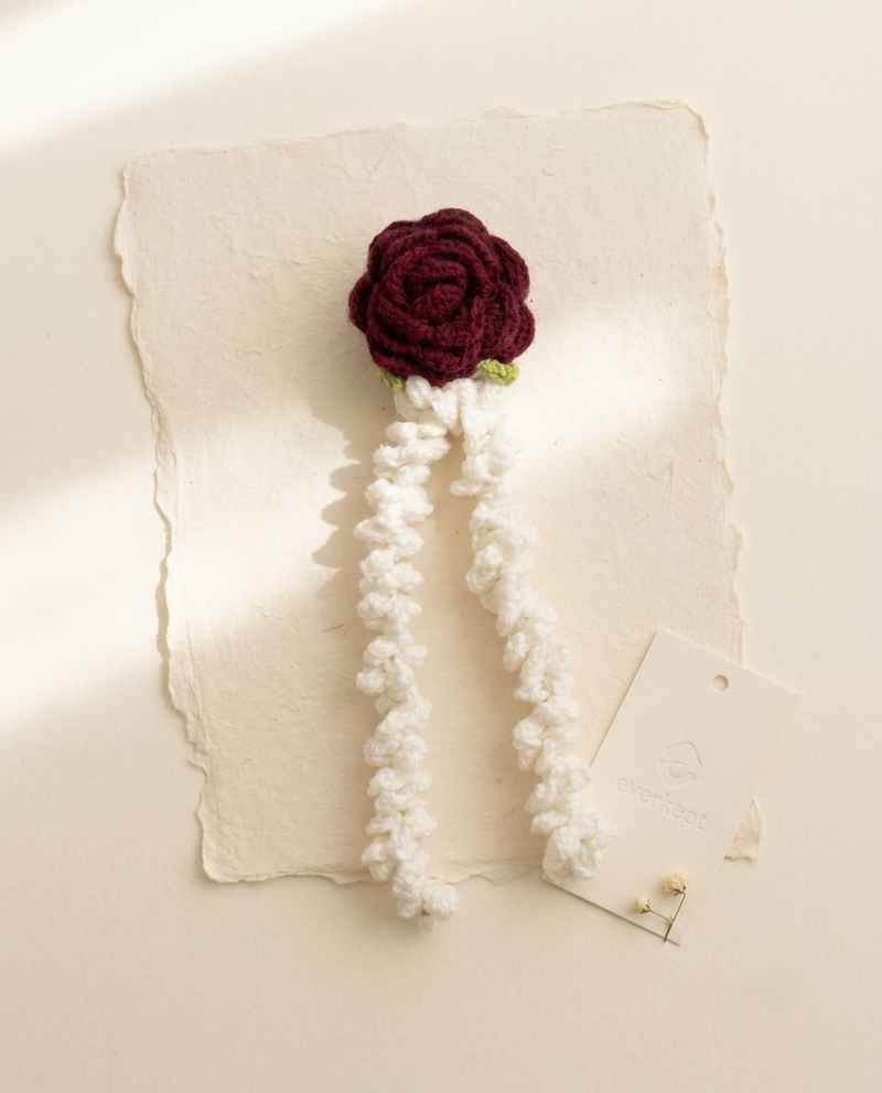 Crochet gajra with a dark red rose and two white mogra strands, on handmade paper with an Everkept tag