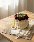 Cream crochet potli bag with a crown of dark red roses, on a wooden table with tissue paper